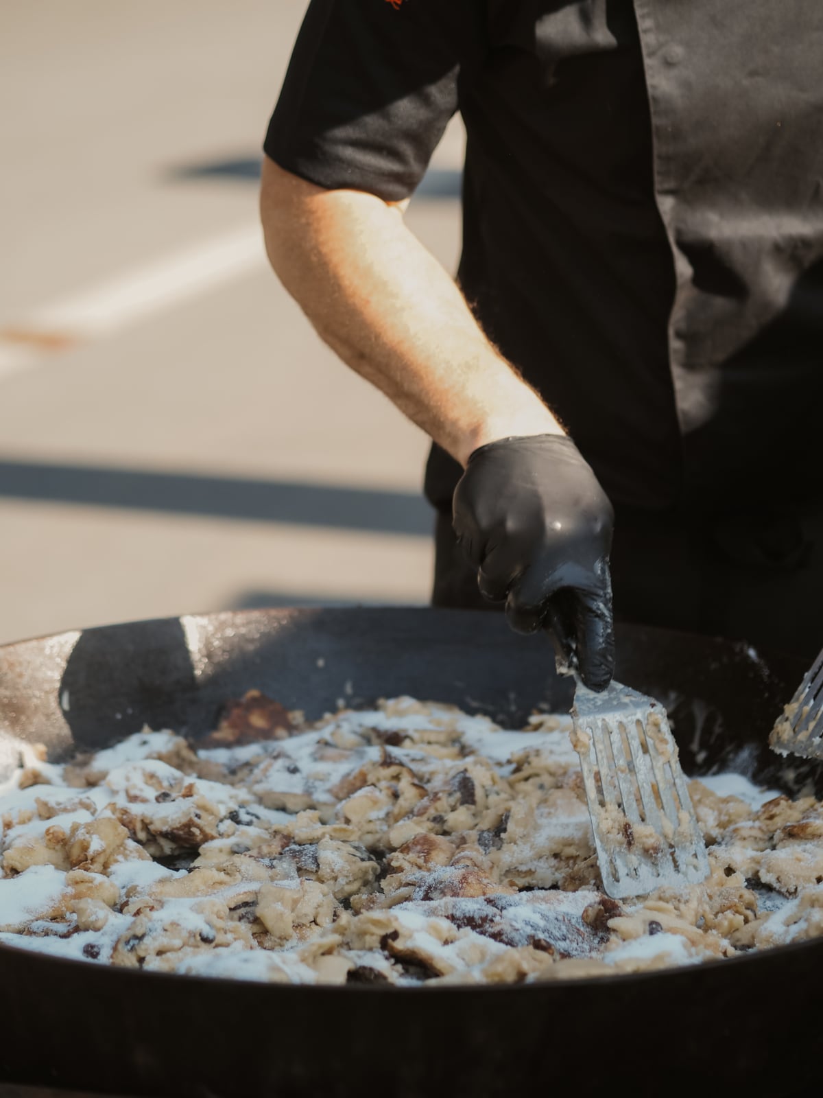 Goldbrauner Kaiserschmarrn mit Puderzucker wird in der großen Pfanne zerteilt
