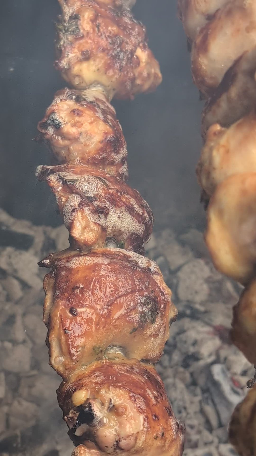 Goldbraun gegrillte Hähnchenunterschenkel am Spieß, glänzend mariniert